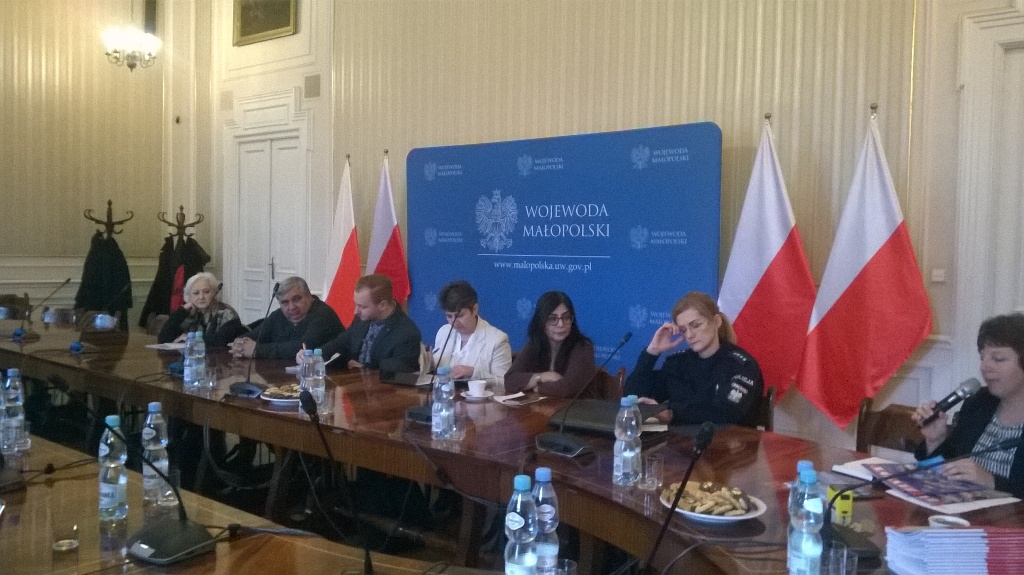 Spotkanie Pełnomocnika z mniejszościami - kilka osób siedzi przy okragłym stole w tle logo wojeowdy i flagi Polski